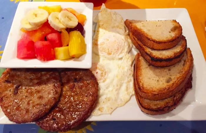Breakfast plate with eggs, sausage, toast and fresh fruit