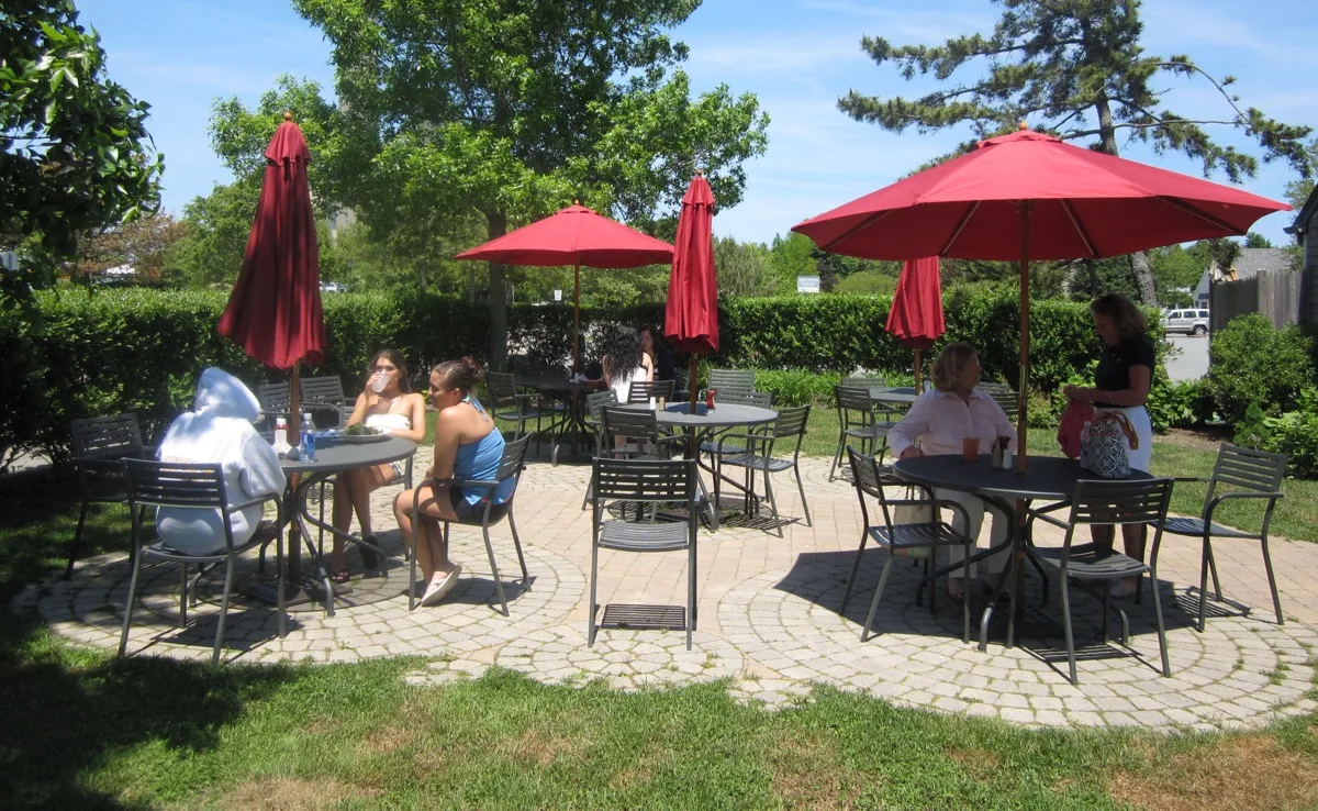 Café Chew outdoor patio seating with red umbrellas on a sunny day